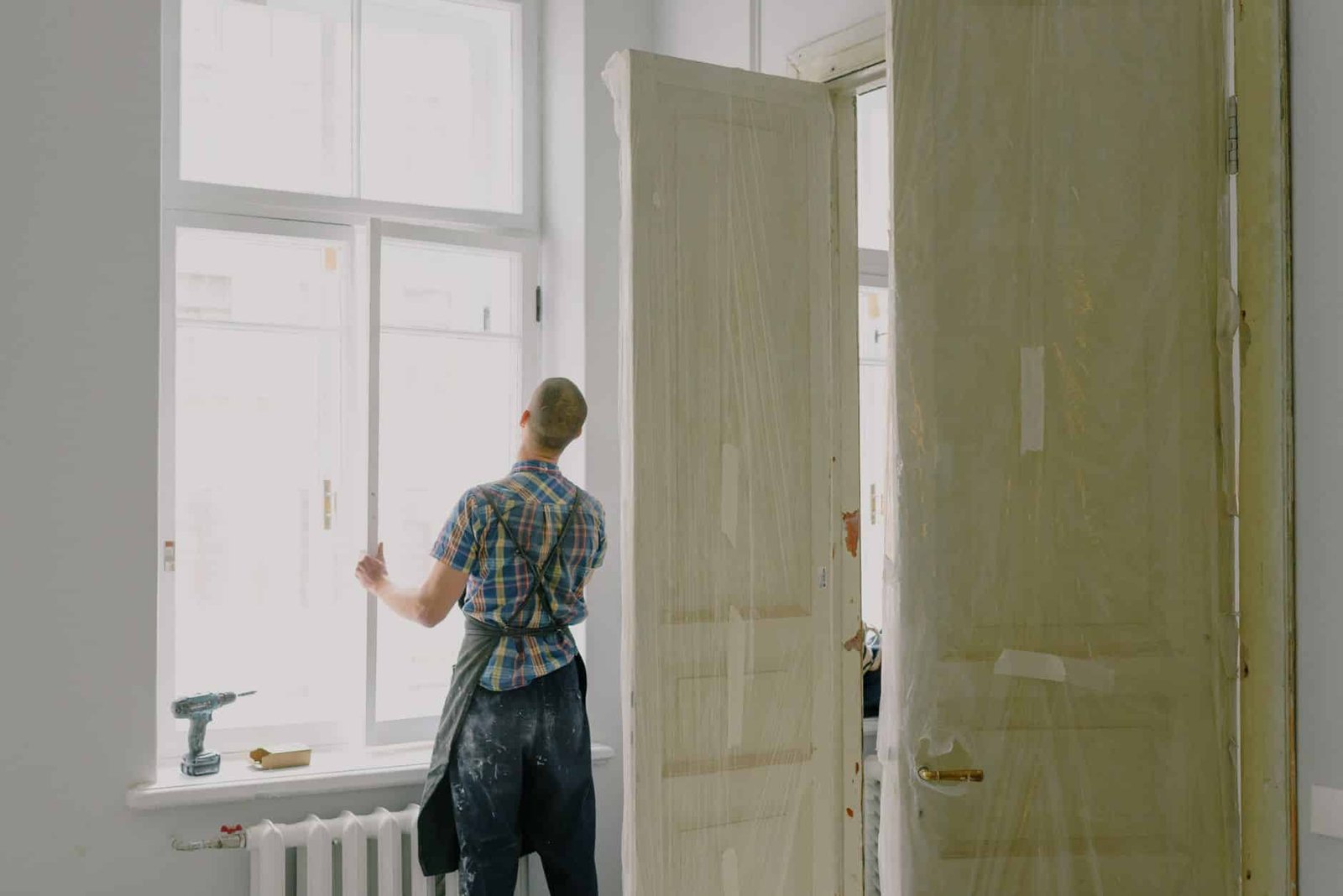 Une personne en tenue de travail dans une piece en renovation