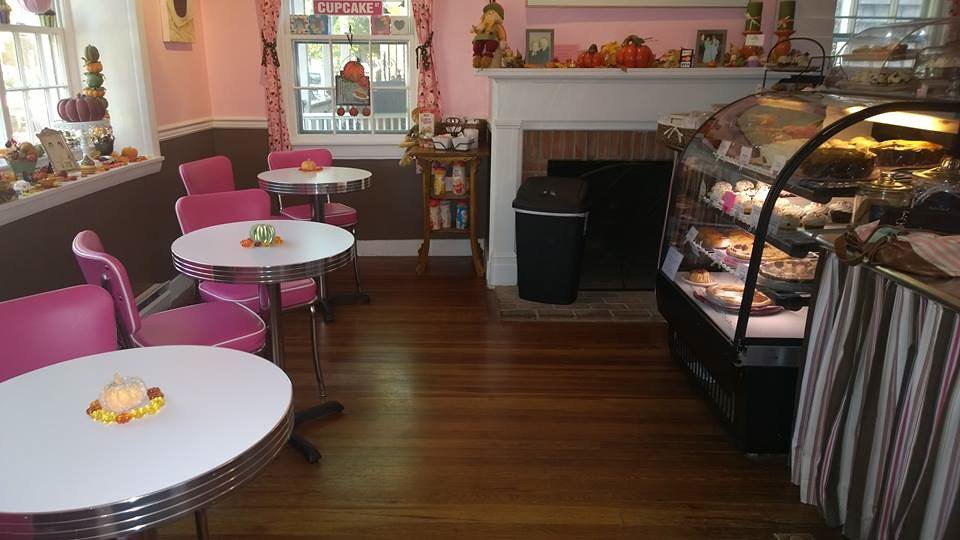 Intérieur d'une pâtisserie avec vitrine réfrigérée, parquet bois et tables de salon de thé