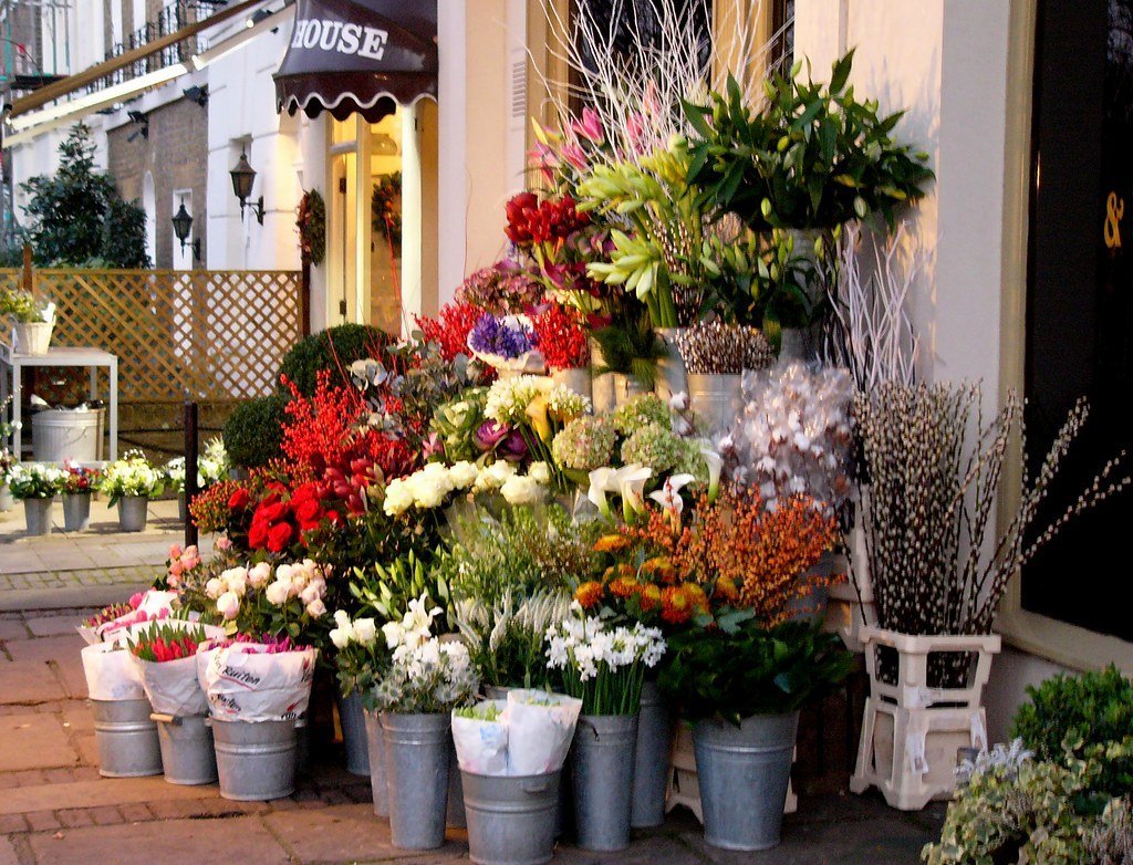 Seaux en zinc garnis de bouquets de fleurs devant une boutique de fleuriste