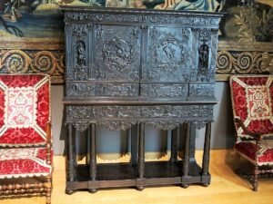 Cabinet en ébène sculpté sur piétement à colonnes torses, portes ornées de scènes en bas-relief, Paris vers 1645, exposé au musée du Louvre entre deux fauteuils recouverts de velours rouge
