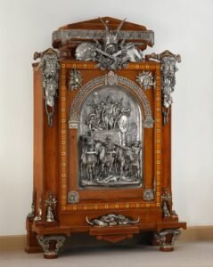 Cabinet monumental en noyer et cèdre marqueté d'ébène et d'ivoire, porte ornée d'un grand bas-relief en bronze argenté figurant un chef gaulois sur un char, montants à têtes d'aurochs et trophée d'armes au fronton
