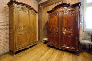 Deux grandes armoires normandes en chêne sculpté à corniche cintrée en chapeau de gendarme, portes à panneaux chantournés ornés de rinceaux et de trophées, dans la salle des armoires du château de Martainville