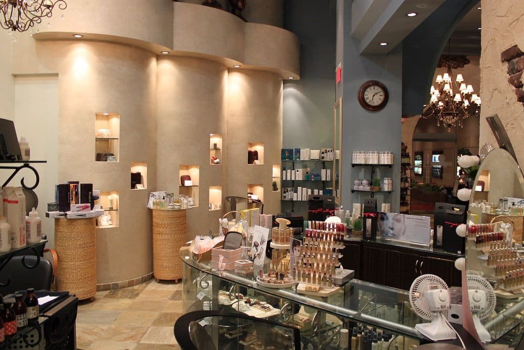 Espace de vente d'un salon de coiffure avec niches éclairées, comptoir vitré et présentoirs